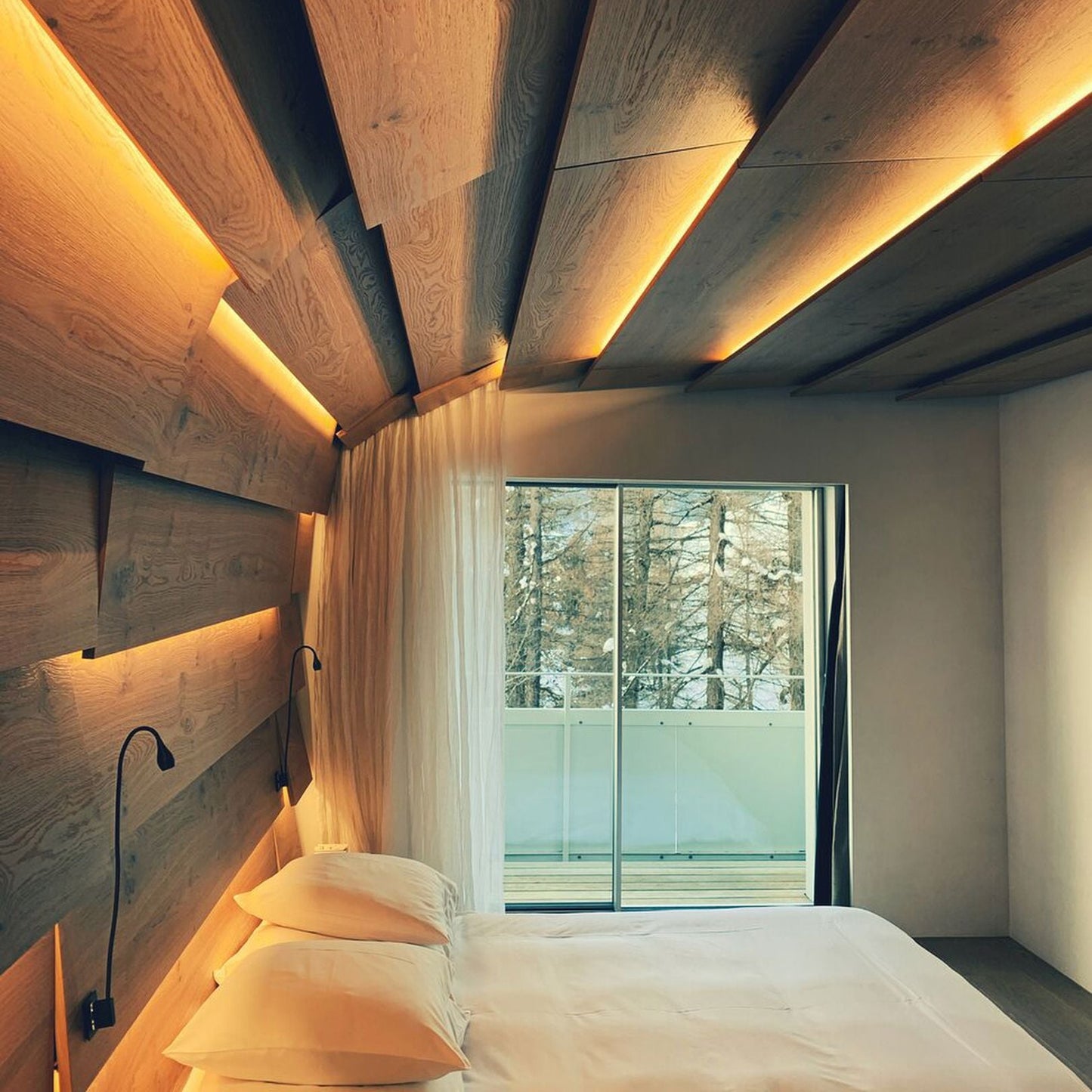 Modern bedroom with wooden ceiling and wall, bed with white bedding, and a window view.