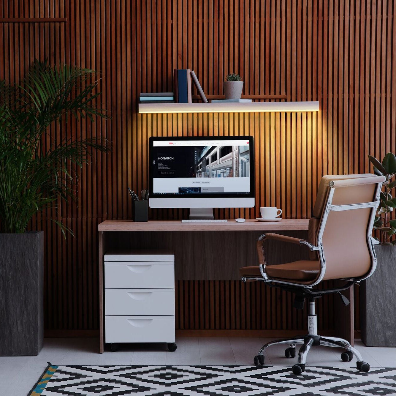 Modern office setup with a desk, chair, and computer monitor against a wooden paneled wall.